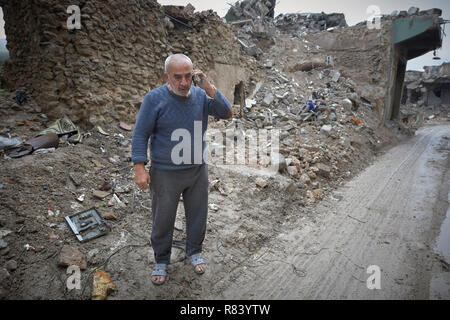 Ein Mann spricht auf seinem Mobiltelefon inmitten der Trümmer der Alten Stadt Mosul, Irak, die während der 2017 Schlacht von Mossul verwüstet wurde. Stockfoto