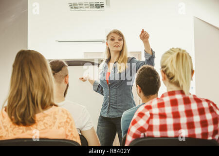 Lehrkonzept. Weibliche Redner vor whiteboard Bildschirm eine Präsentation halten, hören die Teilnehmer Notizen zu machen. Studium Stockfoto