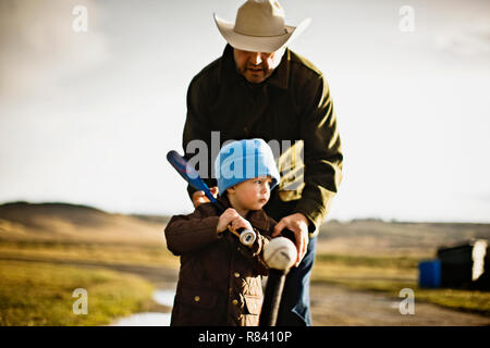 Vater seinem Sohn, wie man die Kugel im T-ball angezeigt Stockfoto