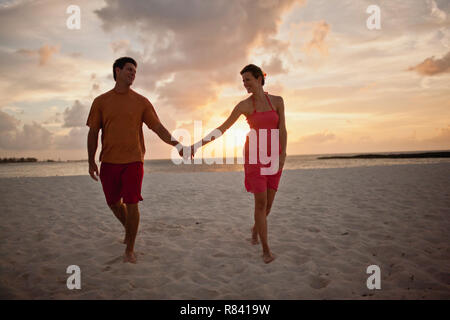 Gerne Mitte nach Paar hält Hände beim Gehen entlang einem Sandstrand. Stockfoto