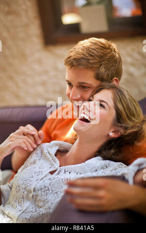 Glückliches junges Paar zusammen sitzen auf einem Sofa. Stockfoto