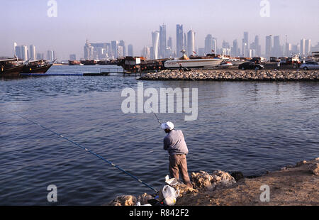 13.09.2010, Doha, Katar - ein Mann ist das Angeln an der Küste entlang der Corniche mit Blick auf die Skyline des Central Business District. Stockfoto