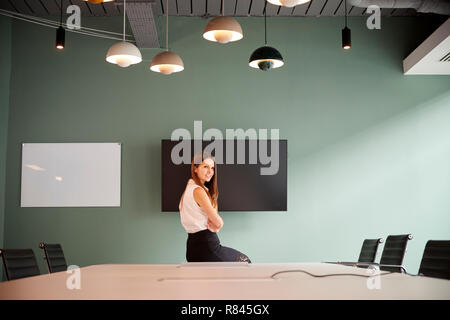 Porträt der jungen Geschäftsfrau Sitzen auf Konferenztisch an Graduate Recruitment Assessment Day in Office Stockfoto