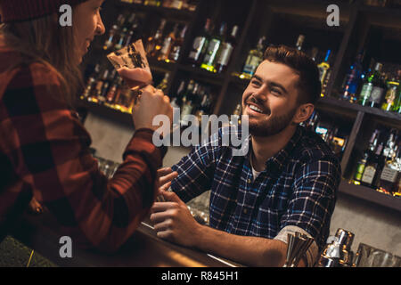 Junge Barkeeper saß an der Theke im Gespräch mit Kunde zufrieden Stockfoto