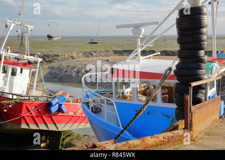 Bunte Fischtrawler festgemacht am Kai mit dem schlammigen Strand bei Ebbe im Hintergrund, Leigh-on-Sea, Großbritannien Stockfoto