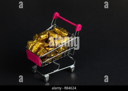 Ein Haufen Gold nuggets oder gold Erz im Warenkorb oder Supermarkt Trolley auf schwarzem Hintergrund, Edelstein oder Klumpen des goldenen Stein-, Finanz- und Stockfoto