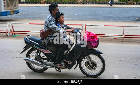 POIPET, Kambodscha - November 24, 2017: zwei Reiter: schreien Asiatischen kleiner Junge, Kind mit einem erwachsenen Mann auf dem Roller Motorrad. Die Grenze zwischen der Kreuzung Stockfoto