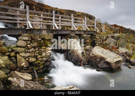 Rustikale Brücke über einem Berg Kaskade bei Cwm Glyderau Idwal im Bereich der Berge in Snowdonia National Park in Nordwales Stockfoto