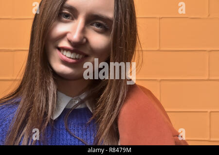 Schönen Porträt, junge attraktive brünette Mädchen, hat schöne Augen und Lippen. Mädchen stehen in einem blauen Pullover mit einem Mantel auf seiner Schulter, n Stockfoto