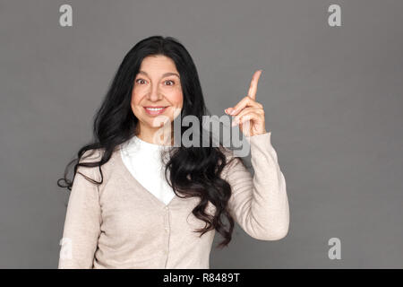 Freestyle. Reife Lady stehen isoliert auf grau Nach oben Suche Kamera begeistert Stockfoto