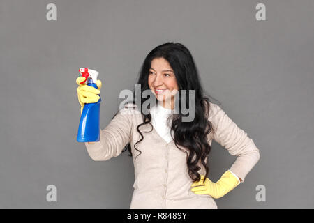 Freestyle. Reife lady in Gummihandschuhe isoliert auf grau Spritzen lächelt Fröhlich stehend Stockfoto
