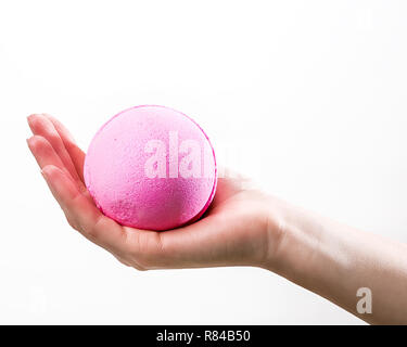 Weibliche Hand, die eine große rosa Badewanne Bombe auf dem weißen Hintergrund Stockfoto