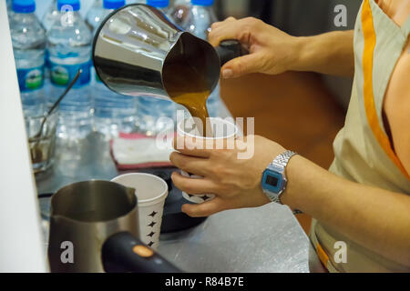 Das Mädchen gießt frisch zubereitete warme, duftende Türkischen Kaffee in einem Glas für den Client. Close-up Stockfoto