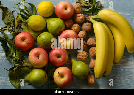 Stapel der Äpfel, Birnen, Nüsse und Bananen auf hellblau Holztisch - Nahaufnahme Stockfoto