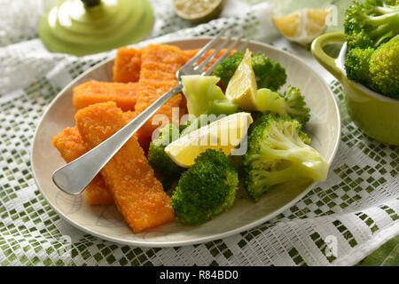 Fischstäbchen mit Brokkoli und Zitrone garnieren - Nahaufnahme Stockfoto