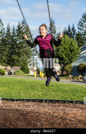 Issaquah, Washington, USA. Zehn Jahre altes Mädchen Schwingen ohne Hände auf einem Spielplatz. (MR) Stockfoto