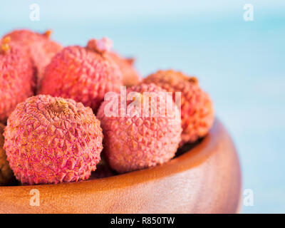 Litschi Obst in Ton Platte auf blauem Hintergrund Holz close up Stockfoto