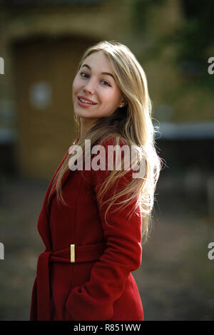 Junge Frau zu Fuß das Tragen der roten Mantel Stockfoto