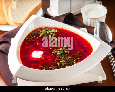 Ucrainian russische traditionelle Rote-Bete-Suppe - borsch in dreieckigen weißen Platte auf dunkelbraunen hölzernen Tisch im Restaurant Stockfoto