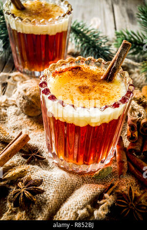 Winterurlaub traditionellen Getränk, hausgemachte heiße Butter rum mit Gewürzen, über alten rustikalen Holzmöbeln Hintergrund mit Weihnachtsbaum Zweige, kopieren Raum Stockfoto