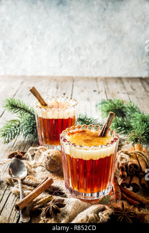 Winterurlaub traditionellen Getränk, hausgemachte heiße Butter rum mit Gewürzen, über alten rustikalen Holzmöbeln Hintergrund mit Weihnachtsbaum Zweige, kopieren Raum Stockfoto