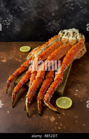 Frische leckere König Kamtschatka Crab Claw mit Zitronenscheiben auf Holz Brett an der braunen Hintergrund Stockfoto