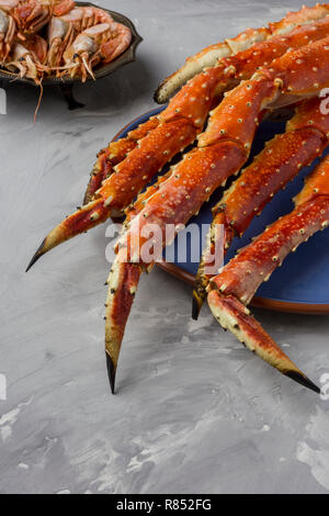 Köstlich frischer Luxus King Kamtschatka Crab Claw auf blauen Platte auf grauem Hintergrund Stockfoto