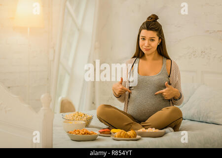 Essen viel während der Schwangerschaft. Die schwangere Frau essen eine Menge verschiedener Lebensmittel Stockfoto