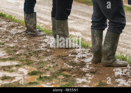 Drei Leute in Gummistiefeln im Schlamm stehen. Stockfoto