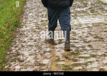 Ein Mann in Gummistiefeln im Schlamm. Stockfoto