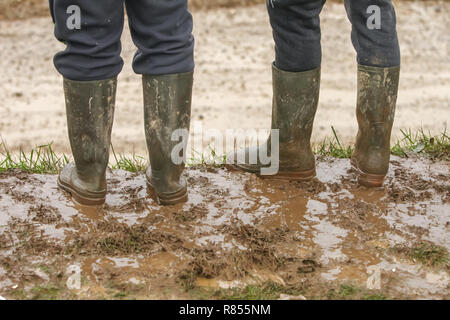 Zwei Leute in Gummistiefeln im Schlamm stehen. Stockfoto