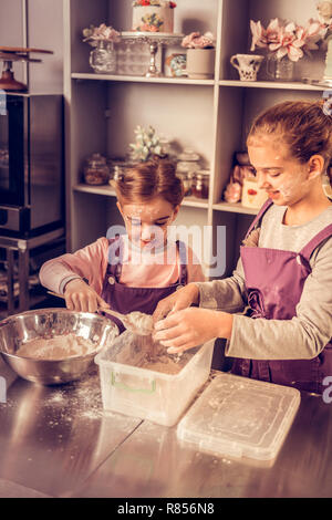 Kuchen Rezept. Freundliche nette Kinder Mischen der Zutaten beim Versuch, einen Kuchen zu machen Stockfoto