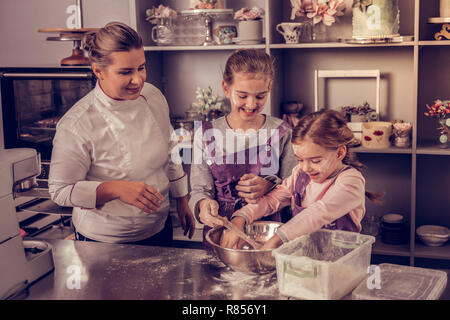 Kochstunde. Positiv glückliche Mädchen, die miteinander sprechen, während im Master teilnehmenden Stockfoto