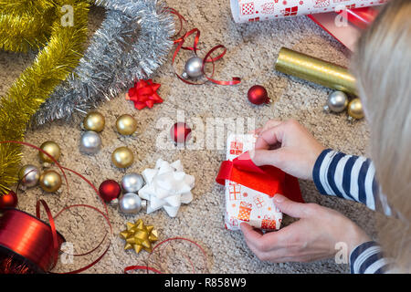 Frau Vorbereitung auf Weihnachten mit Papier und red ribbon vorhanden Stockfoto