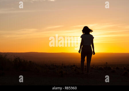 Eine Frau, die zum Sonnenuntergang in der Wüste von Namibias läuft Stockfoto