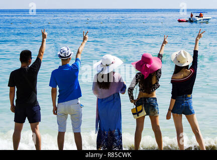 Silhouetten und Gruppe von fünf glücklichen asiatischen Menschen, die auf dem Hintergrund der leeren Sunset Beach. Reisen und meer ferien Konzept und Familie radeln Stockfoto