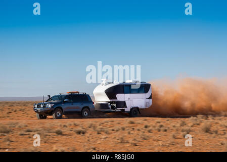 Blau 4wd Toyota LandCruiser Abschleppen groß, off-road Karawane durch Stier Staub auf Outback Australien red Dirt Road. Stockfoto