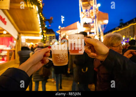 Dresden, Deutschland - 9.12.2018: Weihnachten Becher in Menschen die Hände mit Weihnachtsbeleuchtung auf dem Hintergrund am Weihnachtsmarkt Striezelmarkt in Dresden, Deutschland Stockfoto