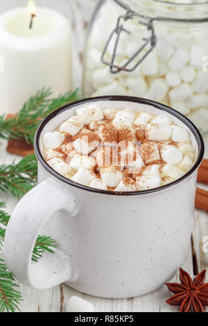 Heißer Kakao (Kaffee oder Schokolade) mit Marshmallows und Zimt in eine weiße Schale. Süßigkeiten, Kerzen und Tannenzweigen auf dem Tisch. Weihnachten. Für das neue Jahr. Rost Stockfoto