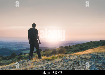 Die Silhouette eines einsamen Mann mit Rucksack über der englischen Landschaft bei Sonnenuntergang. Malvern Hills. UK. Stockfoto