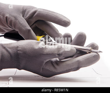 Lötkolben in der Hand auf dem Hintergrund des elektrischen Systems Stockfoto