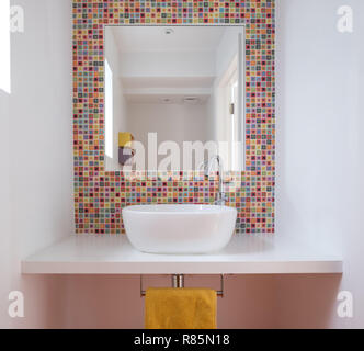 Modernes Badezimmer mit Waschbecken, bunten Glas Mosaikfliesen, lackierte MDF Regal und Spiegel Einfügung in die Fliesen. Stockfoto