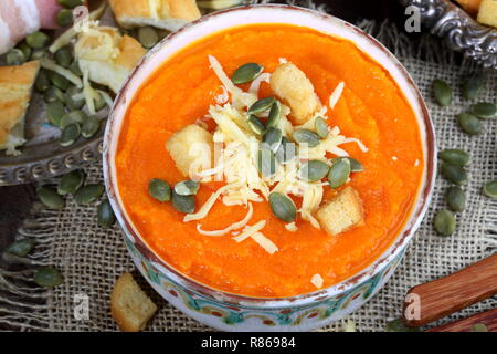 Kürbispüree Suppe mit Crackern, Baguette und Schinken auf hölzernen Tisch Stockfoto