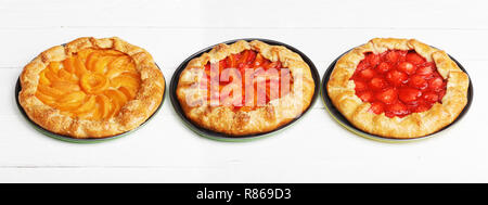 Drei hausgemachten Kuchen mit Pfirsichen und Erdbeeren auf weißem Holztisch. Stockfoto