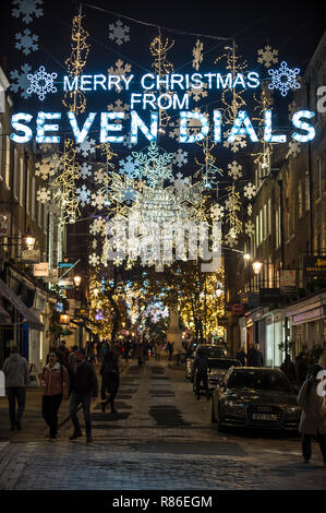 LONDON - November 26, 2018: Frohe Weihnachten Nachricht und Holiday Lights twinkle oberhalb einer malerischen Straße mit Kopfsteinpflaster, die zu den Seven Dials Bezirk. Stockfoto