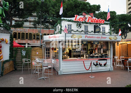 Monte Carlo, Monaco - Dezember 13, 2018: Beleuchtete Weihnachtsmarkt Kiosk Marktstand verkaufen, traditionelle französische Gerichte heißen Kartoffeln, in der Weihnachtszeit Stockfoto