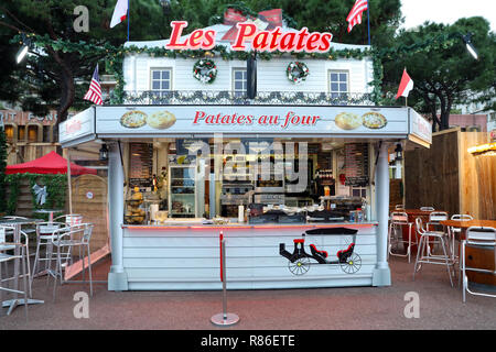 Monte Carlo, Monaco - Dezember 13, 2018: Beleuchtete Weihnachtsmarkt Kiosk Marktstand verkaufen, traditionelle französische Gerichte heißen Kartoffeln, in der Weihnachtszeit Stockfoto