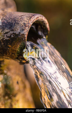 Nahaufnahme der klaren Wasser aus einem offenen Runde rostig alt und abgenutzt Rohr Stockfoto