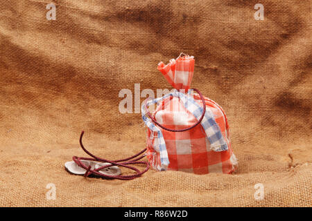 Rote Beutel und Tasten mit Seil auf einem Hintergrund von sackleinen Stockfoto