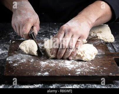 Koch schneidet Weißes Weizenmehl Teig in Stücke mit einer alten Vintage Messer Stockfoto